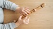 © SimpleDesignStudio - Child playing wooden recorder flute on a wooden table, top view closeup
