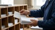 © Domurigu - Person sorting envelopes into wooden mail slots in an office