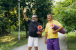 © Roman - Senior men greeting and carrying yoga mats in park