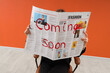 © Pixel-Shot - Person holding a fashion newspaper with 'coming soon' text, new trends and announcements
