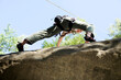 © Westend61 - Young woman mountain climbing, low angle view