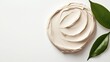 © Tetiana - Cream swirl with natural green leaves, representing skincare and organic beauty ingredients.