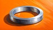 © Koepe - Close up of a metallic ring on orange background.