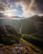 © Travel 'n' Lifestyle - View of the winding road through the mountainous landscape of the Sibillini Mountains at sunset with rocky foreground and dramatic clouds in Bolognola, Marche, Italy.