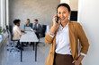 © NDABCREATIVITY - Smiling successful business woman, freelancer, coworker female leader using digital device, phone