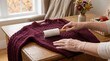 © Tapasii - A close-up of a woman removing lint from sweater using a wooden brush for clothing maintenance and winter garment care articles.