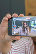 © simona - Young woman recording a playful selfie video on smartphone in a modern kitchen, smiling and holding the phone toward camera while vlogging and enjoying a snack as content creator lifestyle