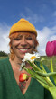 © THAIS VARELA/Stocksy - Smiling person holding flowers in a green field under blue sky