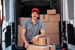 © Nunez Image SL/Stocksy - Smiling delivery man wearing hat with packages