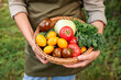 © New Africa - Woman holding wicker basket with fresh vegetables and herbs gathered in own garden outdoors, closeup