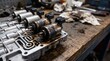 © Abdul Sattar - Damaged transmission solenoids on valve body at auto repair shop. Burnt electronic components on messy wooden workbench with tools, showing mechanical failure and diagnostic process.