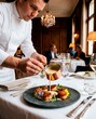 © Vladimir Sazonov - Fine dining chef pouring exquisite sauce over seared scallops in luxury restaurant setting.