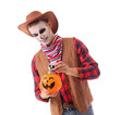 © Pixel-Shot - Young happy man dressed as cowboy for Halloween with human skull and pumpkin lantern isolated on white background