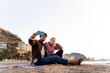 © Alfonso Soler - Couple on winter beach taking selfie with smartphone, enjoying coastal travel