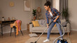 © Prostock-studio - Smiling Young Black Woman Engaged In Vacuuming Carpet In Bright Living Room, Creating A Clean And Tidy Space While Enjoying The Cleaning Process In A Comfortable Home Environment.