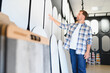© Serhii - Man choosing decorative plaster samples in showroom for home renovation