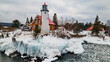 © Amazing Aerial - Aerial view of the historic Eagle Harbor Lighthouse surrounded by snow-covered rocky shores and icy waters of Lake Superior in Eagle Harbor, Michigan, United States.