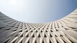© SUHEB - Low angle view of a modern building facade with a geometric triangular pattern and sharp architectural lines against a clear blue sky background