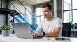 © tanin - A man engaging in AI research and development in a modern office space during daytime hours