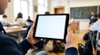 © Juan - Student holding a tablet with a blank white screen in a busy classroom