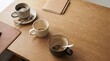 © zokov_111 - Three empty coffee cups rest on a warm wooden table, with one nearby notebook and a pen. Soft sunlight filters in, inviting creativity and calm.