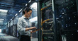 © Gorodenkoff - Asian Woman Network Engineer Using Laptop Computer for Server Configuration and Cable Management Beside an Open Rack Cabinet in a Big Modern Data Center Hosting Cloud Storage and AI Supercomputers.