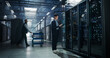 © Gorodenkoff - Asian Male Systems Administrator Holding Tablet Computer at Open Server Rack While Colleague Transports Hardware on Cart, Storage Capacity and Firmware Updates in AI Cloud Computing Data Center