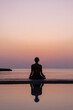 © Anna Berkut/Stocksy - mindfulness, silhouette of woman practicing meditation at sunset
