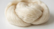© Maham - Soft off white raw organic wool fiber bundle resting on a clean studio surface showing delicate textures and light shadows