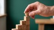 © mdamjad - Hand placing a small crown on top of a wooden block staircase representing business success