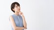 © Daya Saji - Thoughtful young Asian woman looking up with hand on chin while thinking or worrying, standing against a white studio background with copy space