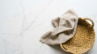 © qay - Wicker basket with beige linen napkin on white marble background, top view, perfect for food styling, culinary content and kitchen interior design