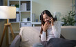 © matinee - Happy young Asian woman talking on a smartphone while relaxing with coffee at home.