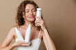 © SHOTPRIME STUDIO - A serene middle aged woman with natural skin tests skincare products, holding white bottles. A candid moment of authentic beauty, selfcare, and mindful daily routine.