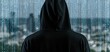 © ckybe - In a futuristic urban setting, a lone figure in a black hoodie is immersed in cascading blue binary code representing digital security.