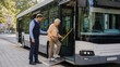 © ISVO - Elderly woman assisted by male bus driver using a wheelchair ramp to board a public transport bus on a city street with trees in the background