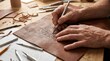 © Razzaque - Artisan carving intricate patterns into brown leather with a precision craft knife tool.