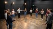 © David - Group of teenage students participating in an acting workshop and performing creative icebreaker exercises in a black box theater rehearsal studio