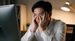 © Maryna - Stressed Asian businessman sits at desk rubbing eyes in front of computer monitor. Overworked male employee feels exhausted, frustrated by heavy workload. Tired pro suffers from burnout, mental