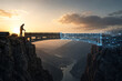 © cgrove - Industrial bridge engineer stands on cliff edge at sunset overlooking digital construction grid overlay symbolizing civil engineering and future infrastructure