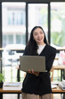 © SOMKID - Asian businesswoman thinking and working with a laptop in the office.