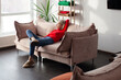 © Tatyana Gladskih - Relaxed mature woman resting on a comfortable sofa at home. Cozy living room lifestyle with natural light, comfortable clothing, peaceful leisure and residential interior concept.