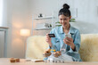 © Ratirat - Happy woman shopping online with smartphone and credit card at home, using e-commerce and mobile payment with miniature carts, packages for convenient digital retail delivery.