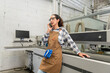 © BESTIMAGE - Female carpenter wearing safety glasses talking on smartphone near CNC machinery in woodworking factory Technician woman talk by cell phone inside modern carpentry plant during work production