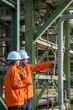 © BESTIMAGE - Technician teamwork consulting petroleum engineering in oil refinery project operation brainstorm at fuel industrial plant Two workers holding laptop and pointing near oil pipeline structure