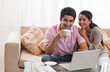 © IndiaPix - Portrait of happy young couple smiling with laptop and coffee cup