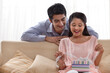 © IndiaPix - Surprised young woman unwrapping gift with man at home