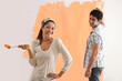 © IndiaPix - Portrait of beautiful woman smiling with man painting wall in background