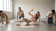 © Rendara Studio - Playful woman falling backward during a group pilates class in a studio