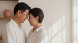 © OCTOLENS - Middle-aged Asian couple smiling and touching foreheads affectionately indoors at home